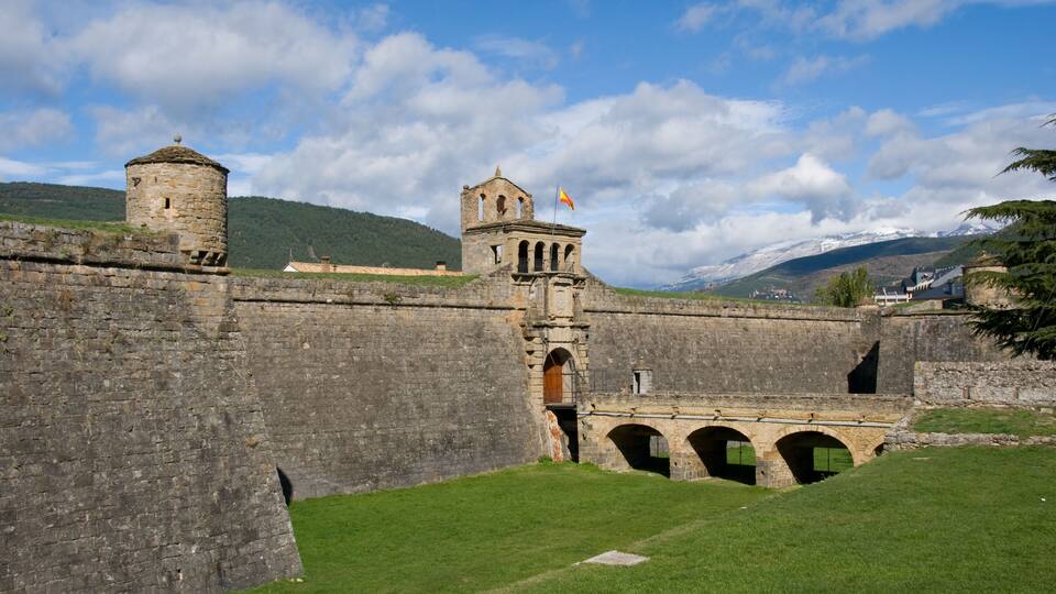 A historic stone fort with a watchtower, arched bridge, and a flag.