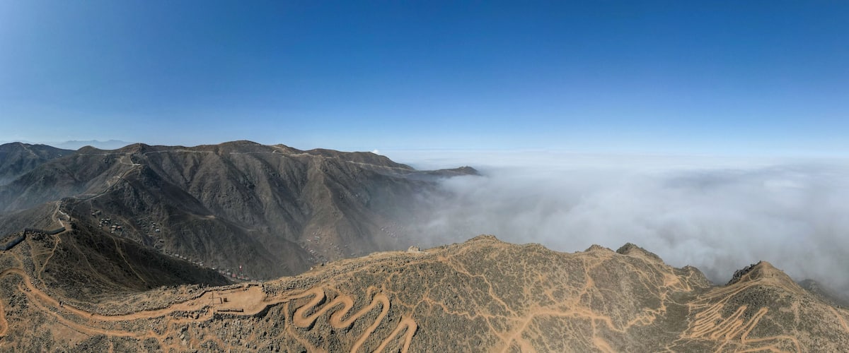 A mountainous landscape with winding trails and a village at the base.