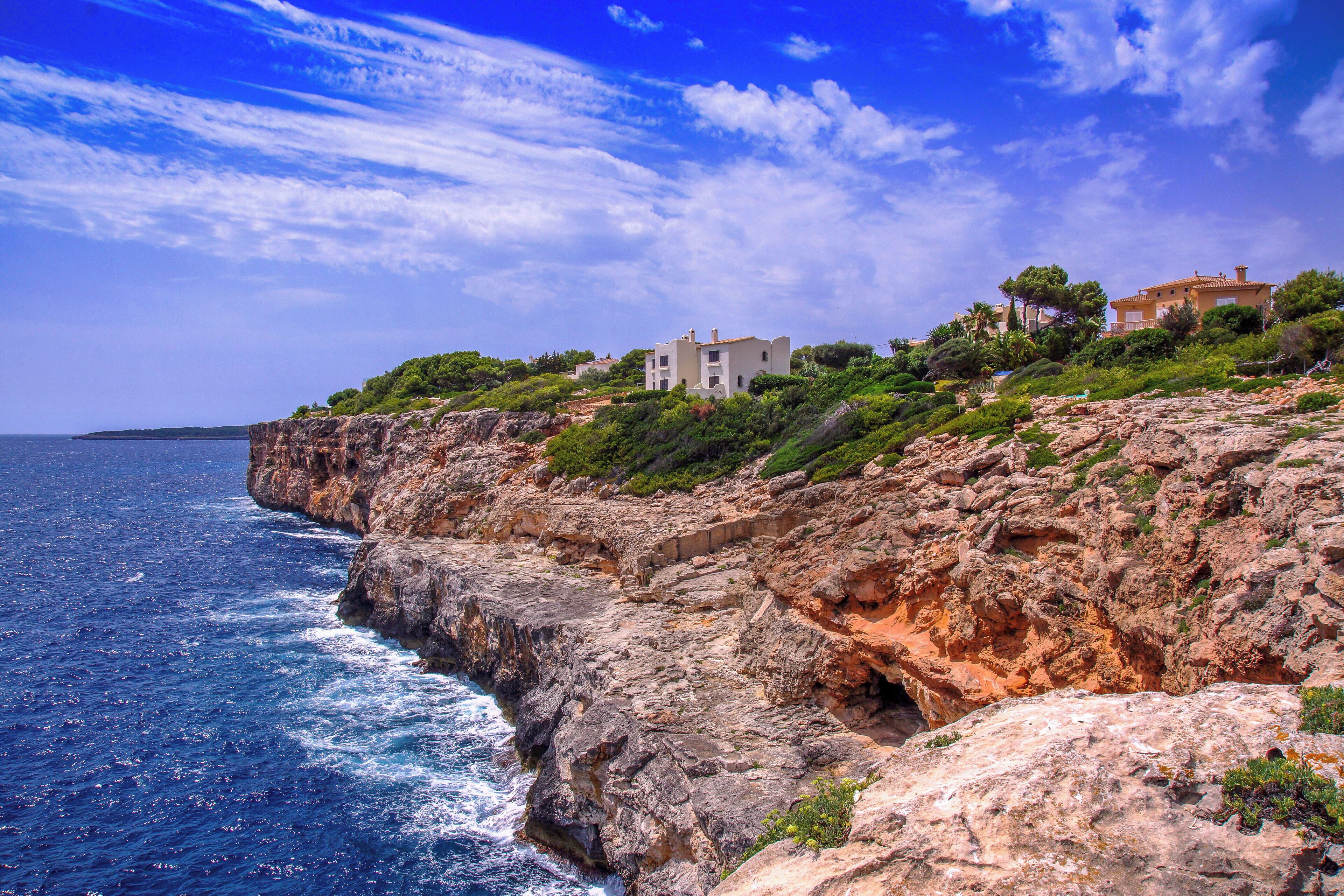 A coastal cliff with a white building and lush greenery.