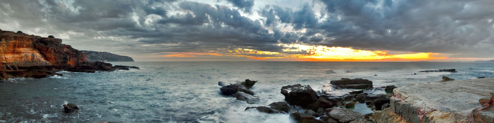 A coastal landscape with rocky cliffs and waves crashing against the shore.