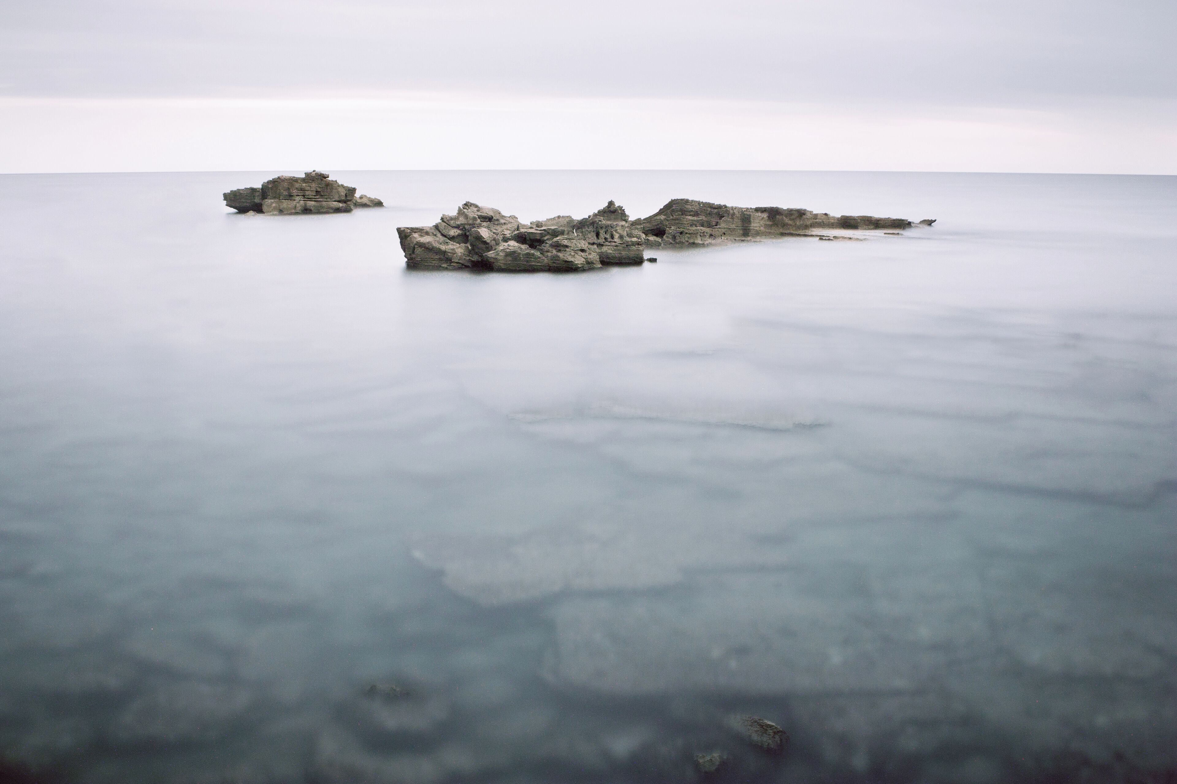 A calm sea with rocky formations.