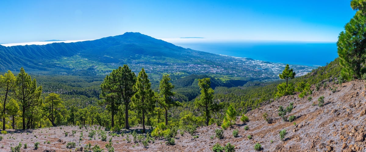 A mountainous landscape with a view of a coastal town and a large mountain in the background.