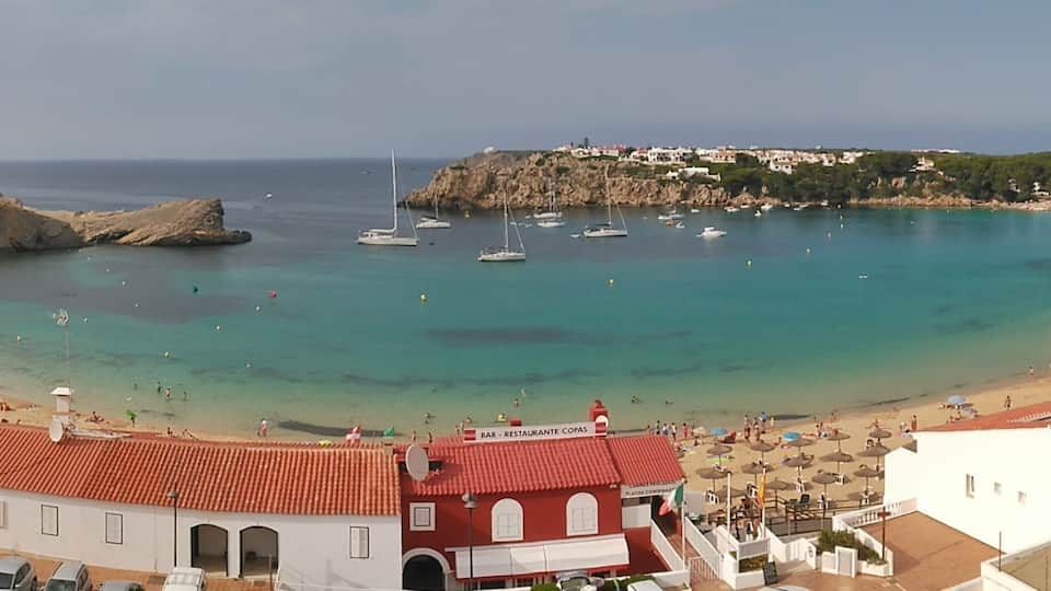 A coastal town with a beach, boats, and buildings.