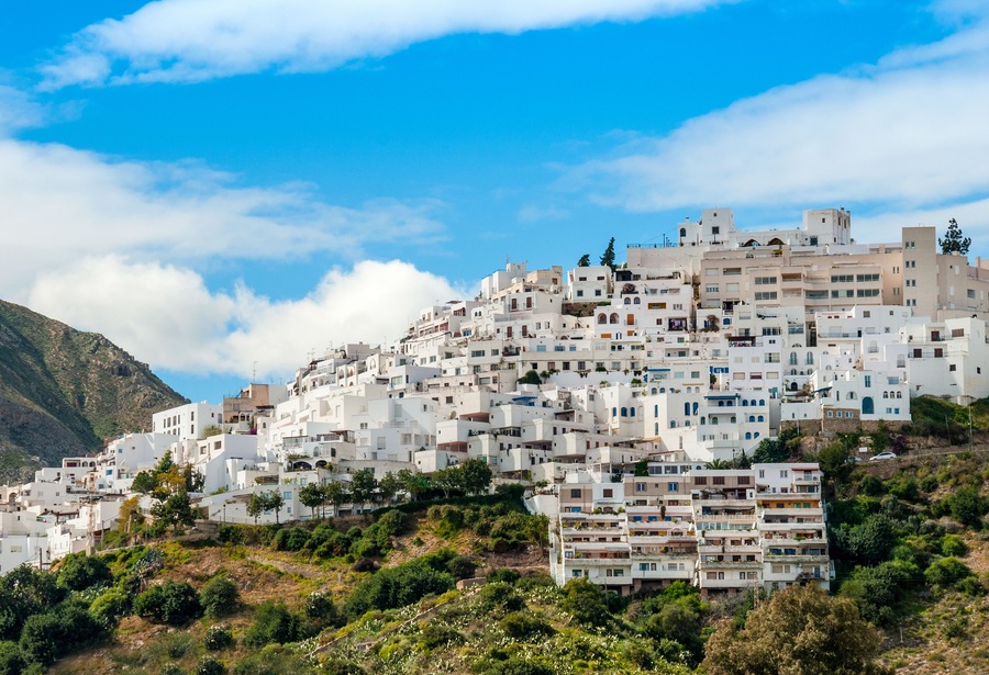 Una ladera llena de edificios blancos con una montaña al fondo.
