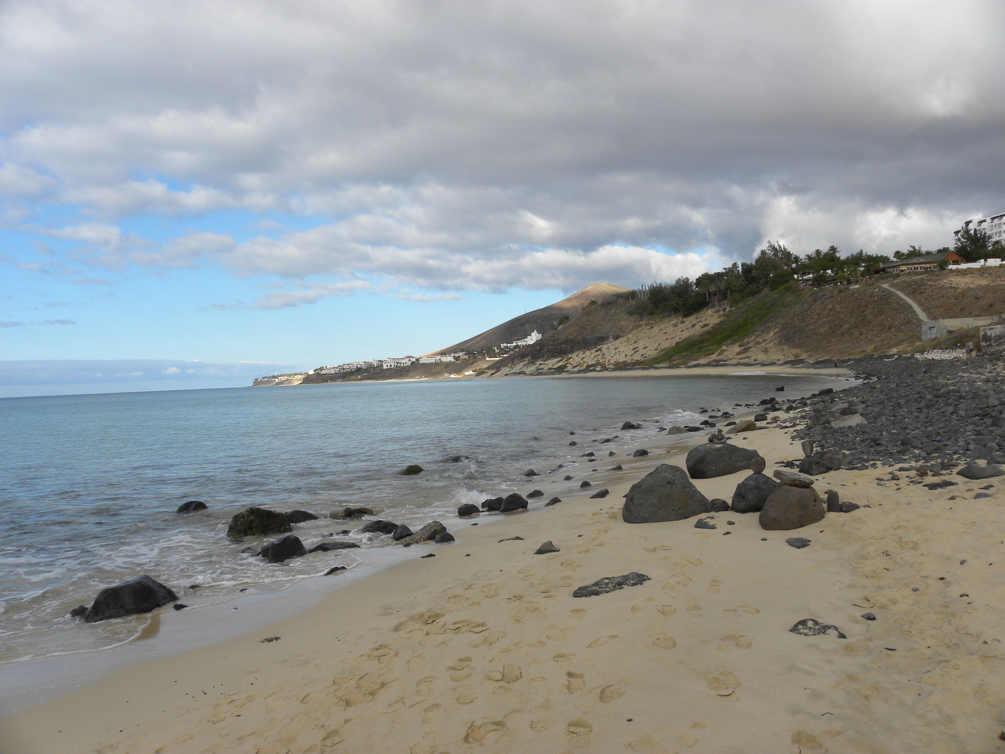 A beach with rocky shoreline and footprints in the sand.