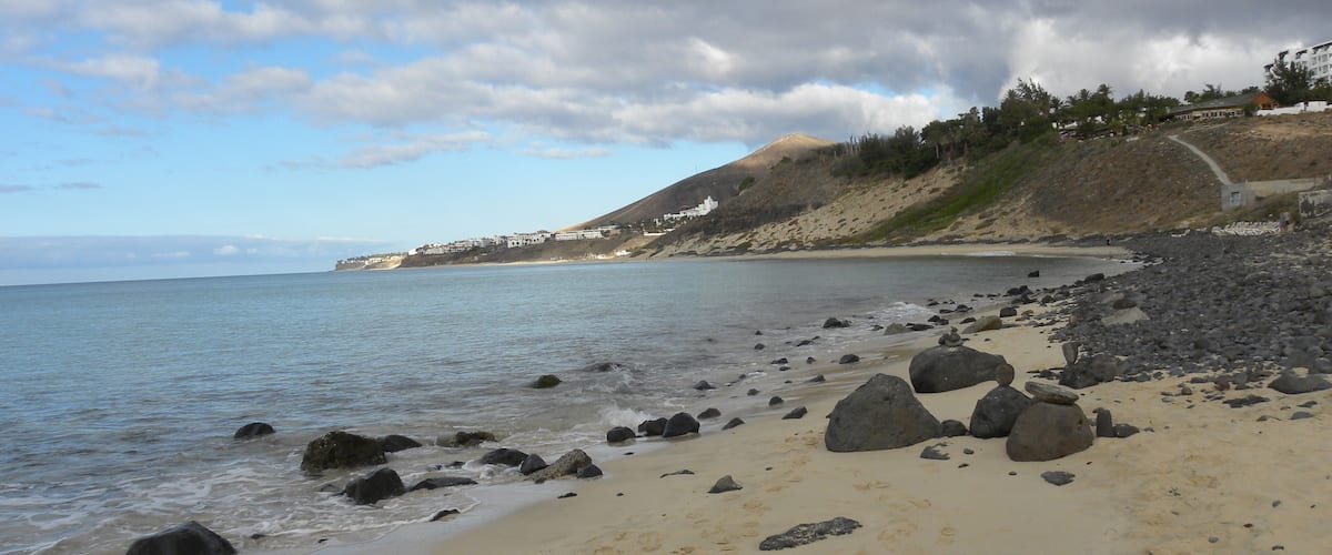 A beach with rocky shoreline and footprints in the sand.