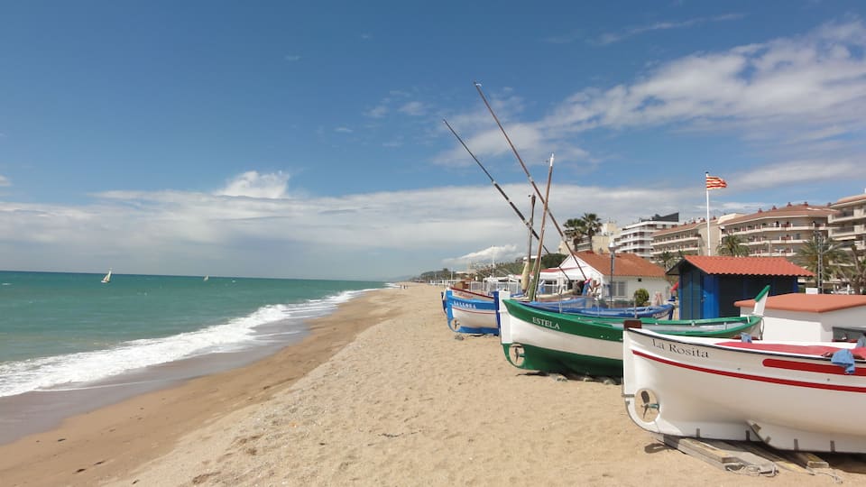 A sandy beach with several boats moored along the shore.