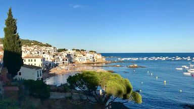 A coastal town with white buildings, a beach, and boats in the water.