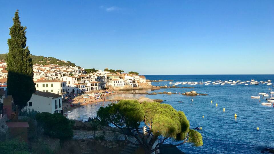 A coastal town with white buildings, a beach, and boats in the water.