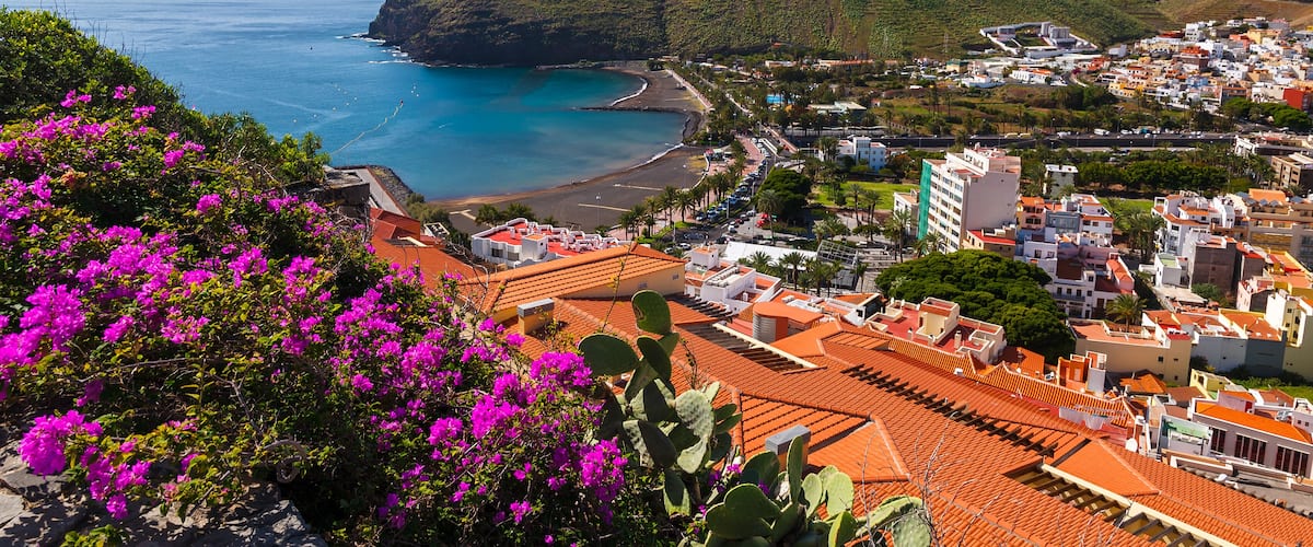 A coastal town with a beach, buildings, and hills.