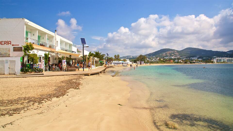 A beach with clear turquoise water, a sandy shore, and a building with a sign reading "ERIA".