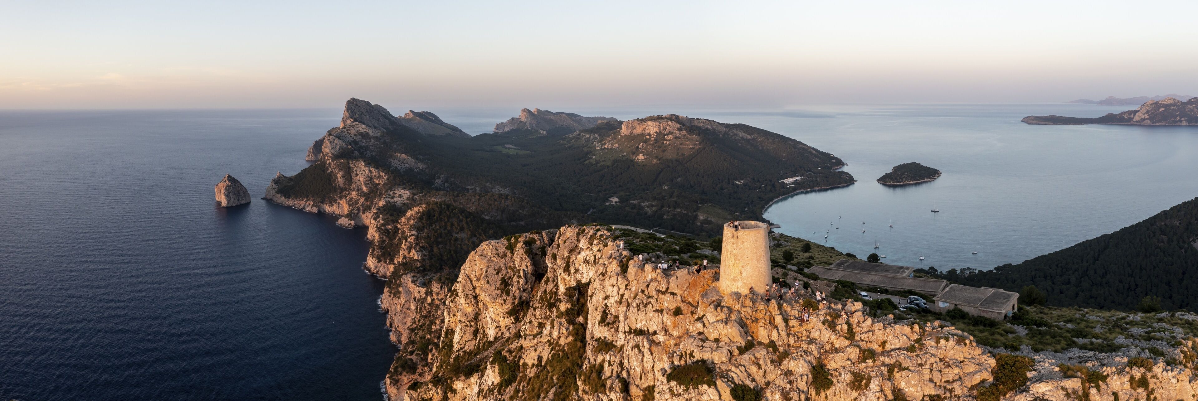 A coastal landscape with rocky cliffs, a lighthouse, and a calm sea.