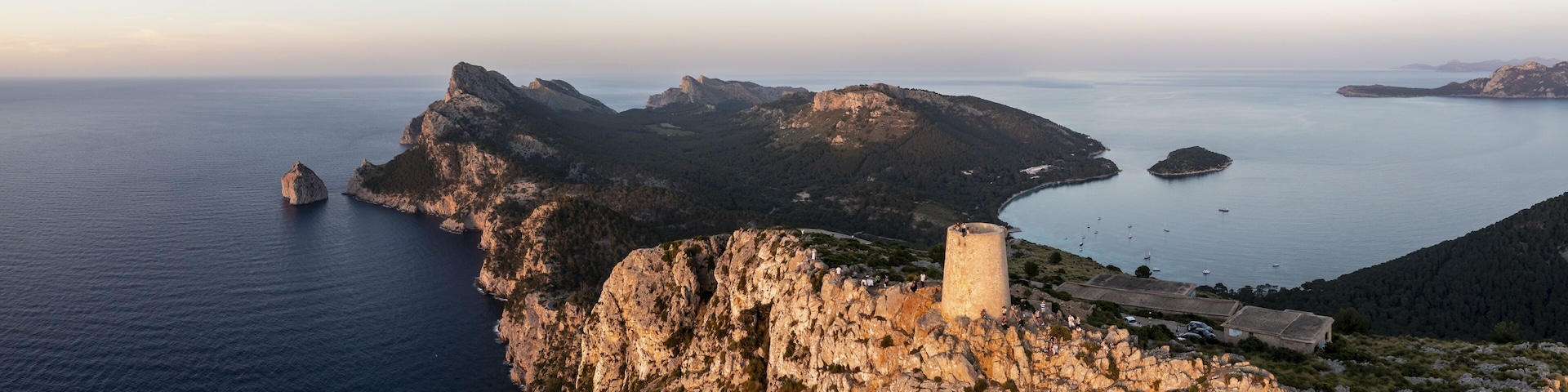 A coastal landscape with rocky cliffs, a lighthouse, and a calm sea.