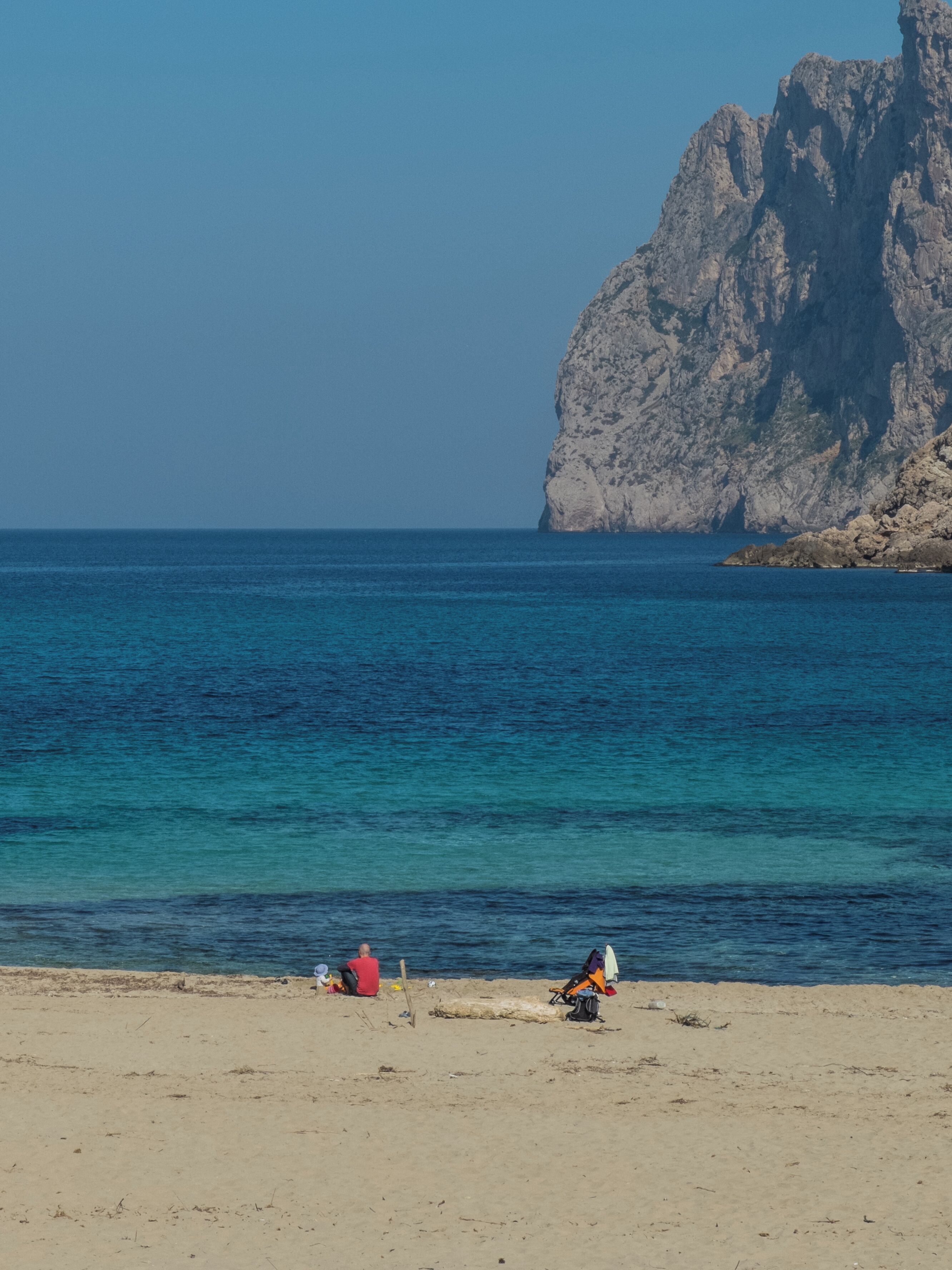 A beach with a rocky cliff in the background.