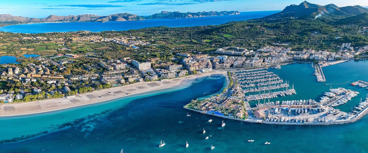 An aerial view of a coastal city with a marina, beaches, and surrounding hills.