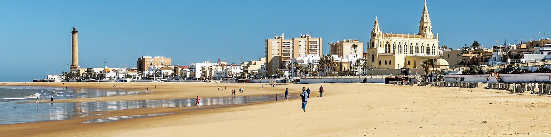 Chipiona, Cadiz, Spain-June 2016. Tourists walking along the beach of the turistic municipality of the coast of light in Cadiz on a sunny day.