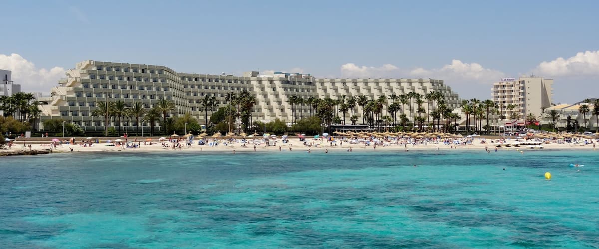 A beachfront hotel with a pool and beach umbrellas.