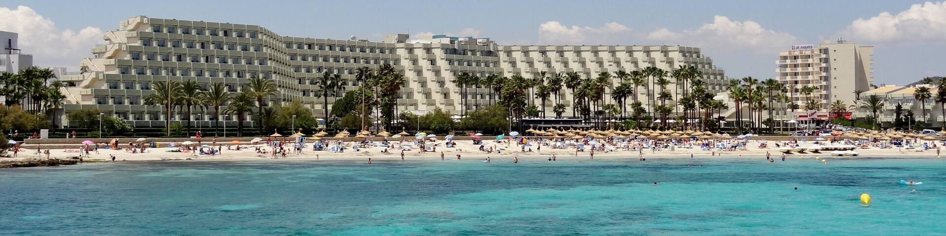 A beachfront hotel with a pool and beach umbrellas.