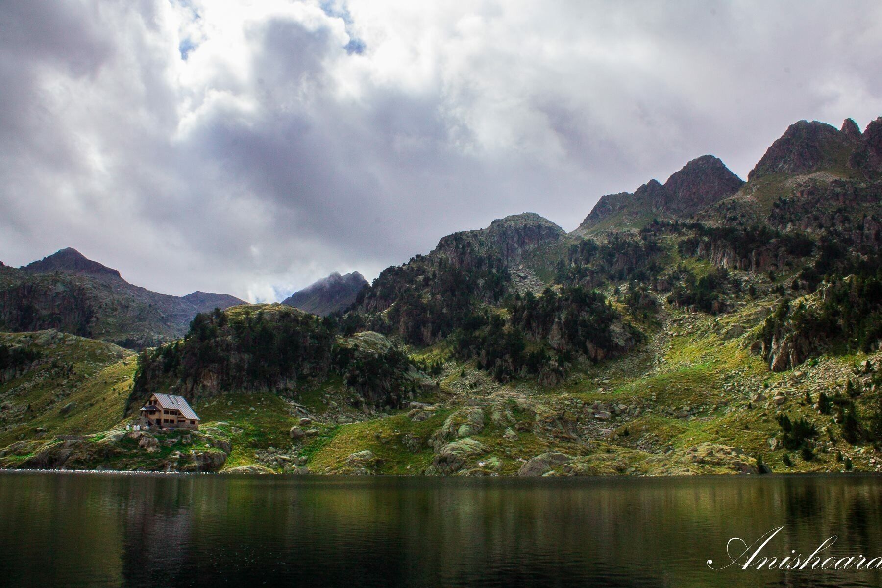 A mountainous landscape with a lake and a house on a hill.