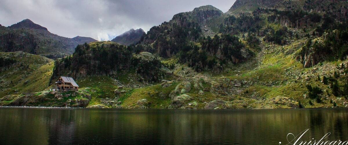 A mountainous landscape with a lake and a house on a hill.