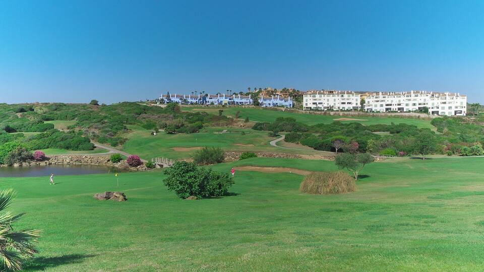 A golf course with a large building in the background.