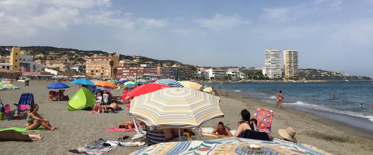 A beach with colorful umbrellas and people sunbathing.