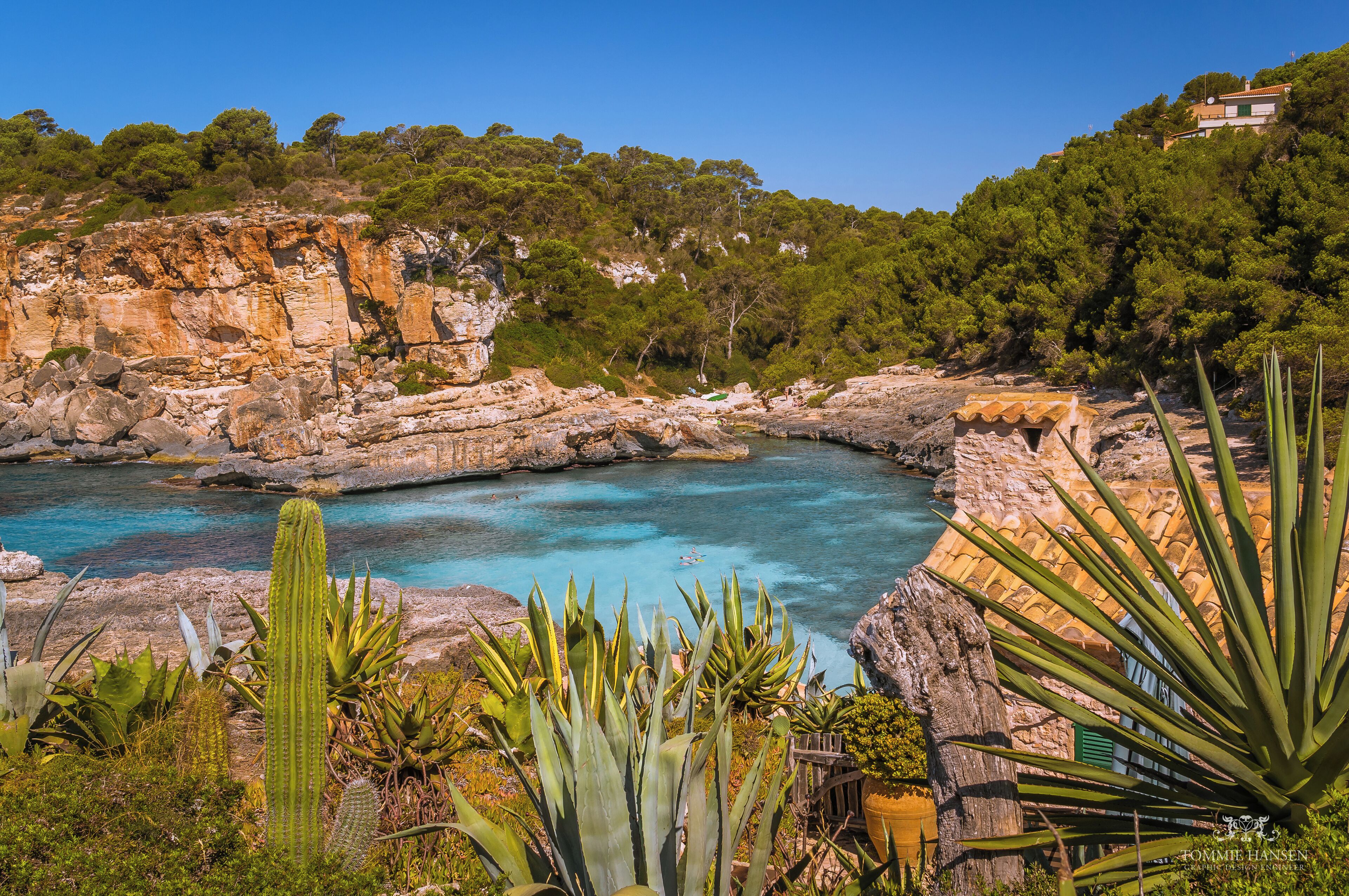 A coastal landscape with rocky cliffs, clear turquoise waters, and lush greenery.