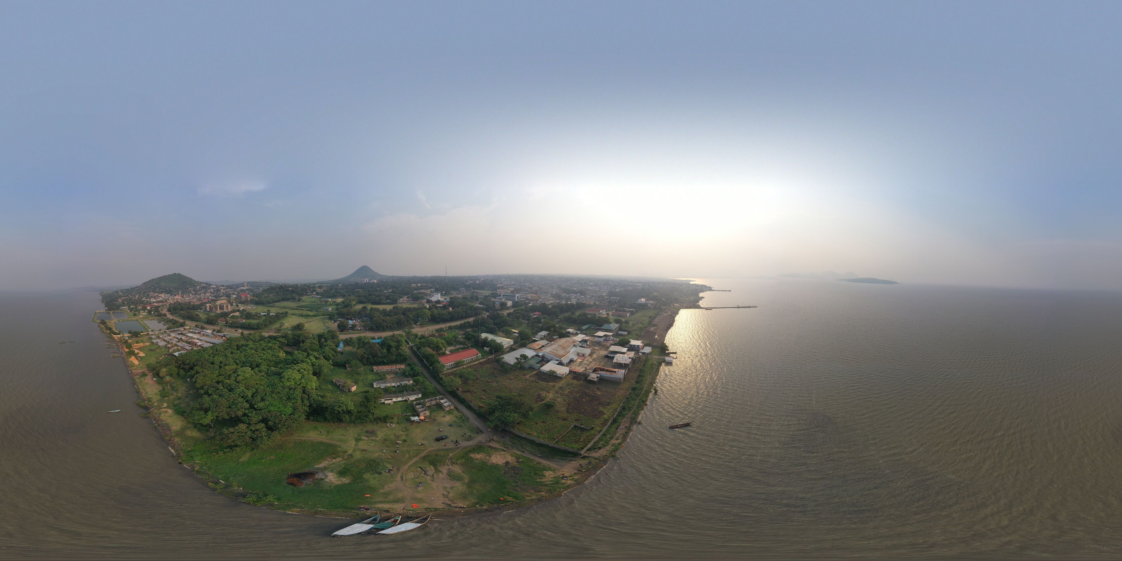An aerial view of a coastal town with a prominent mountain, a river, and several boats.