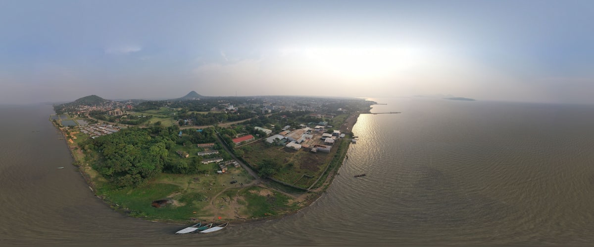 An aerial view of a coastal town with a prominent mountain, a river, and several boats.