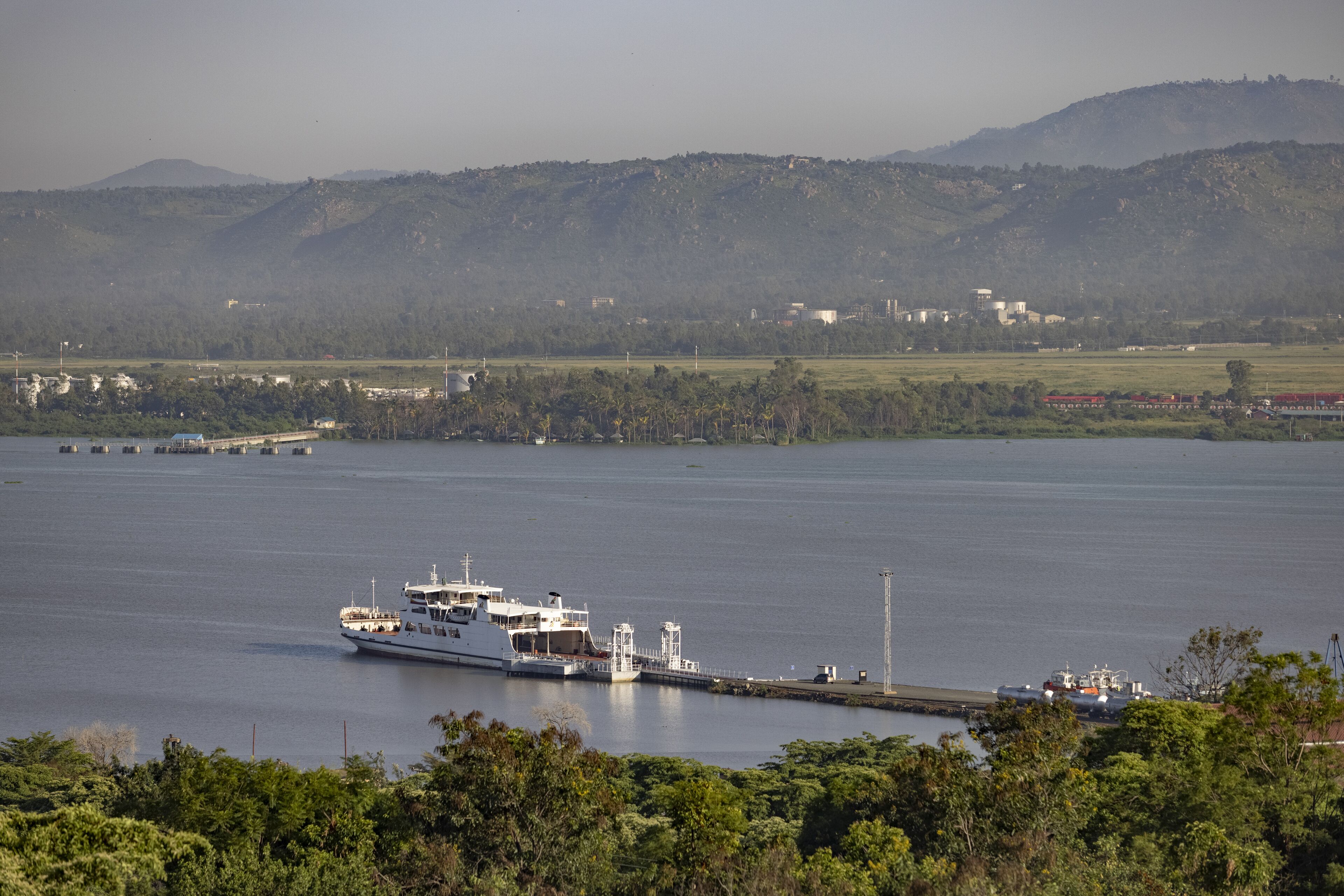 Kisumu, Kenya - 13 May 2021: View of a ferry docked at a pier on Lake Victoria, the tranquil waters reflecting the soft morning light against the backdrop of distant hills.
