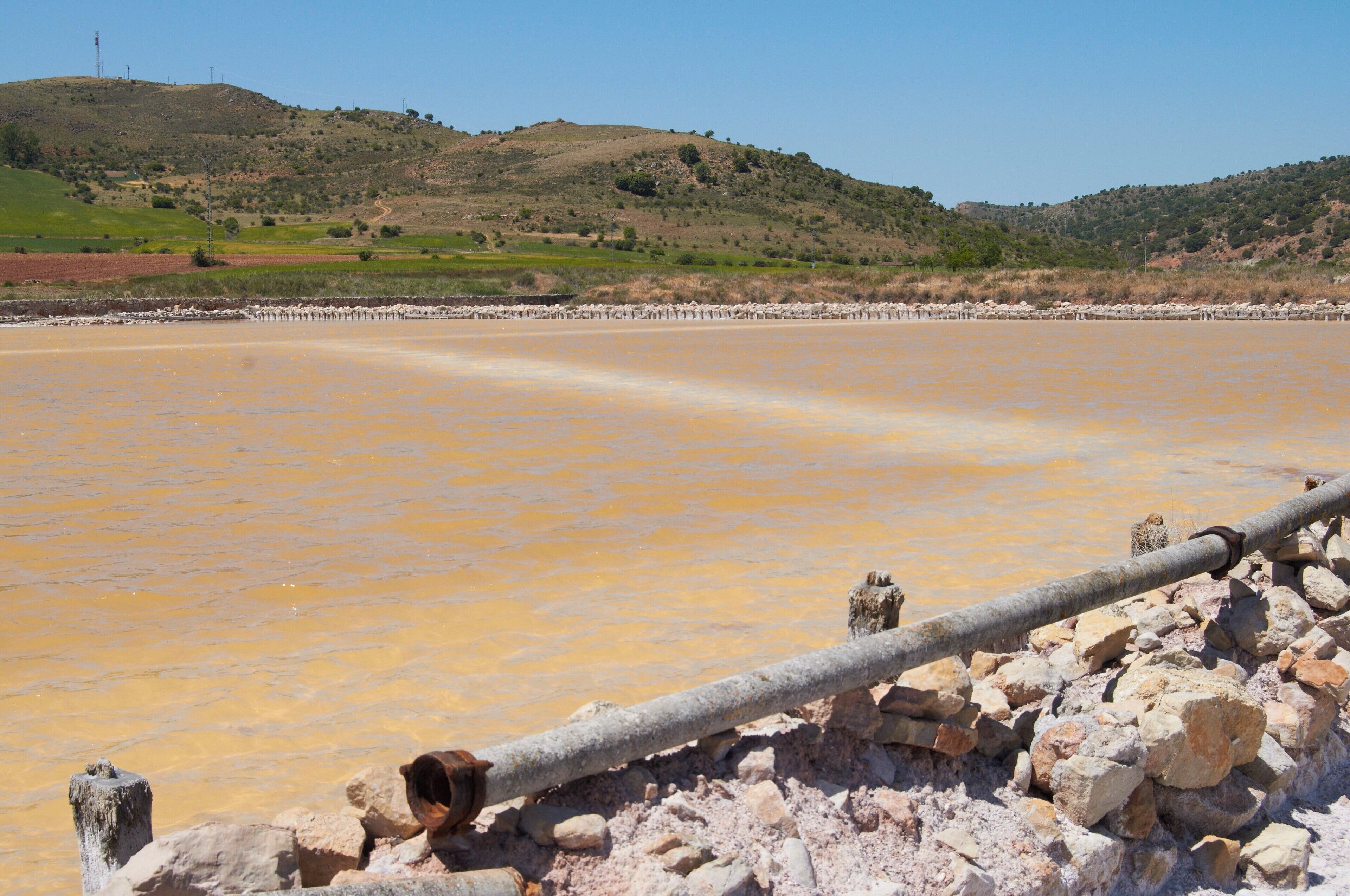 A salt flat with a pipeline and rocky foreground.