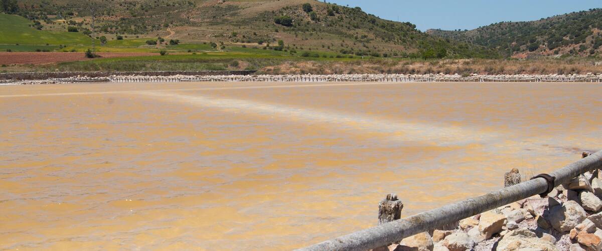 A salt flat with a pipeline and rocky foreground.