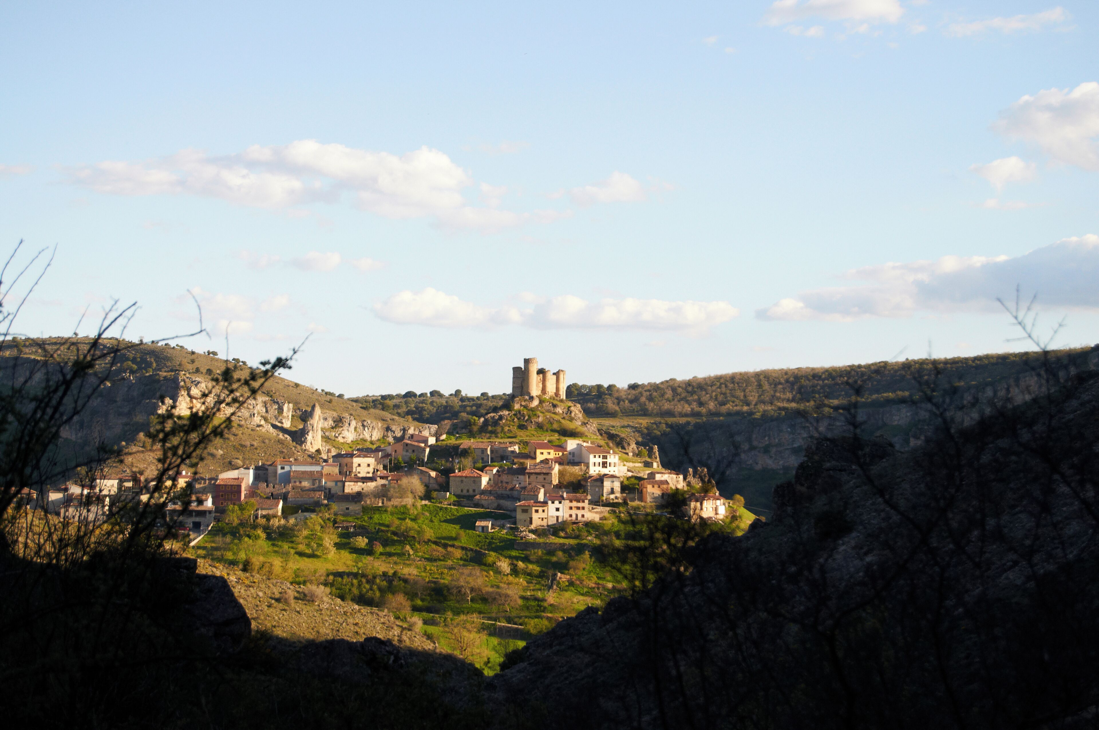 A village nestled in a valley with a prominent castle on a hill.