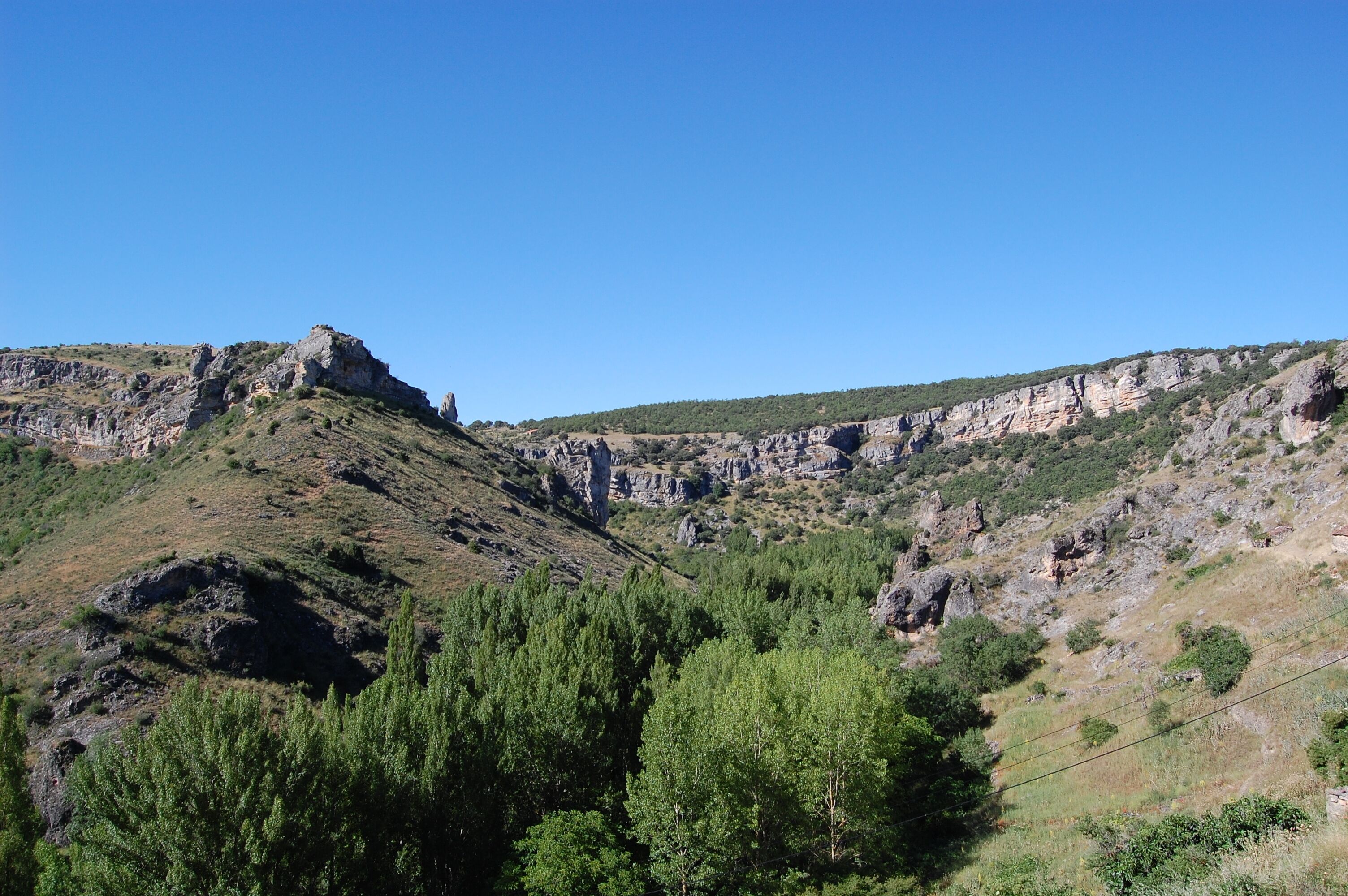 A mountainous landscape with rocky cliffs and dense green forests.