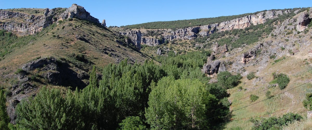 A mountainous landscape with rocky cliffs and dense green forests.