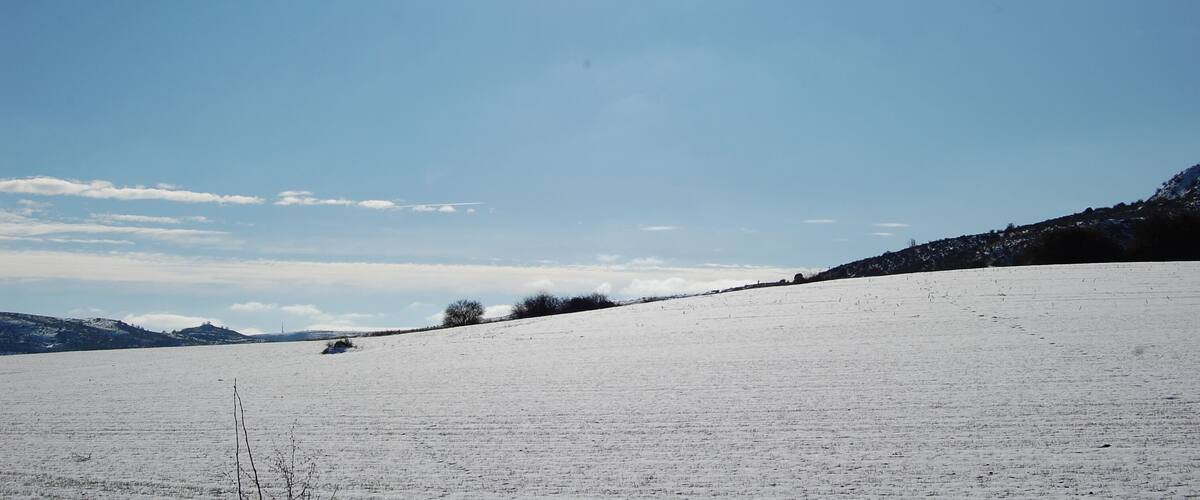 A snowy landscape with a clear sky and distant mountains.