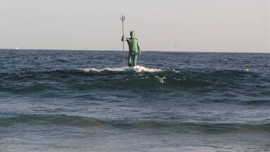 Estátua de uma figura segurando um tridente, erguida no oceano.