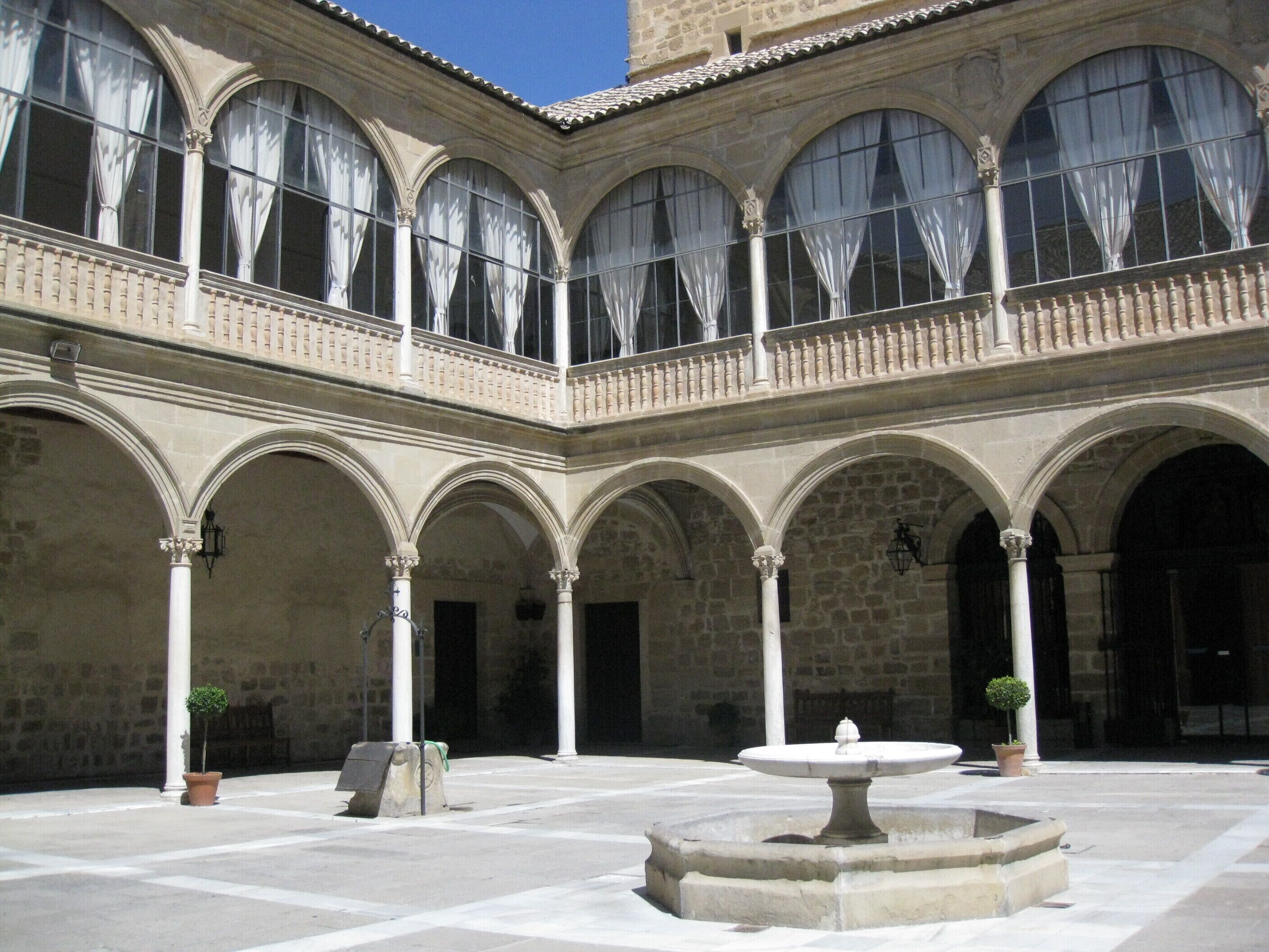 A courtyard with a fountain, arches, and columns.