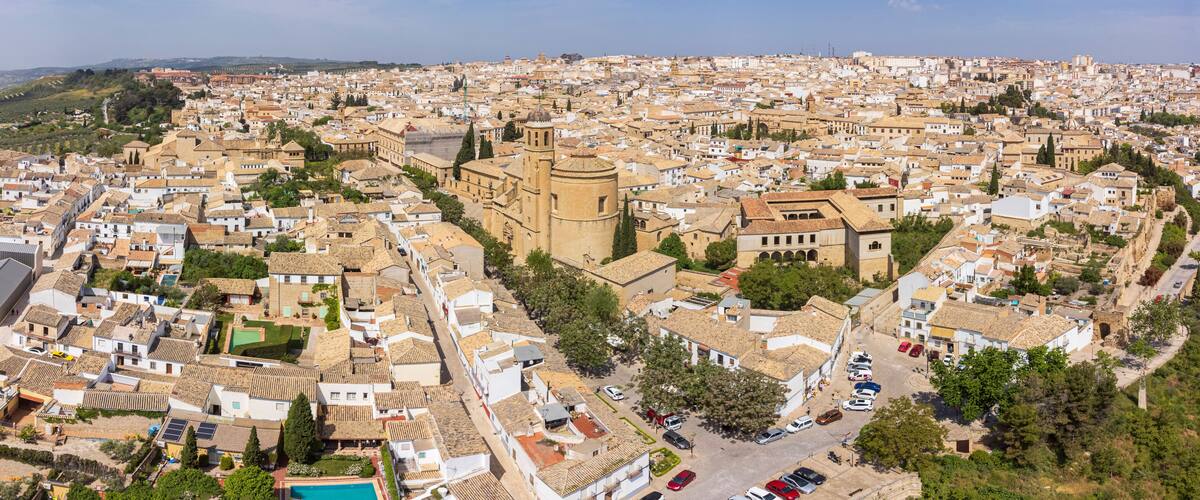An aerial view of a densely populated city with historic architecture, including a prominent tower and a church.