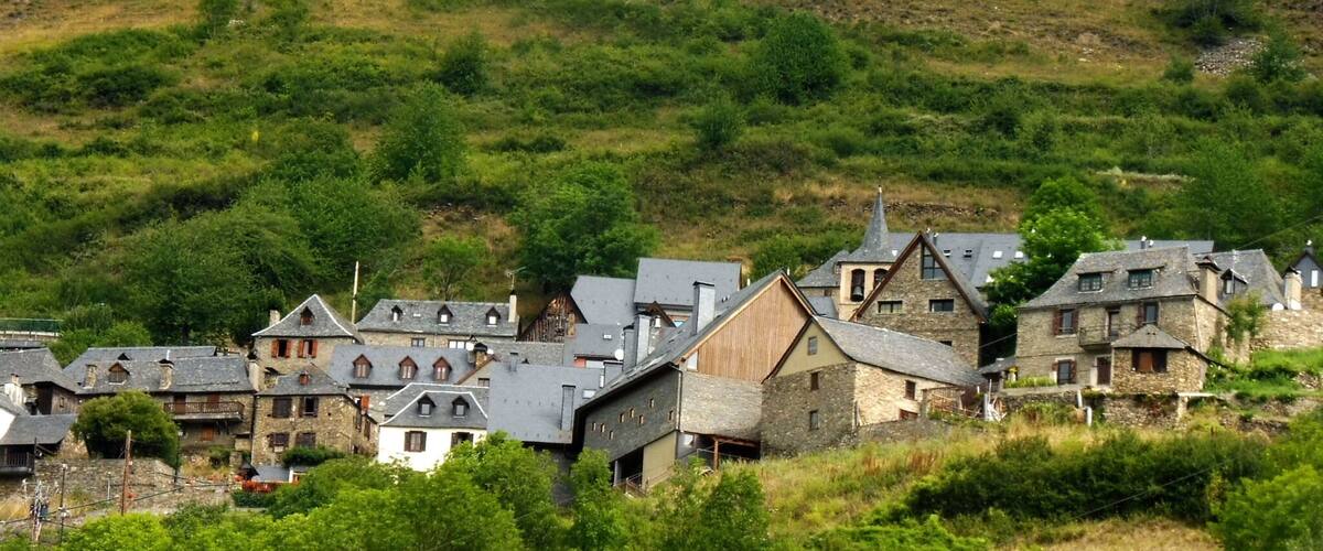 A village with stone houses and a church on a hillside.