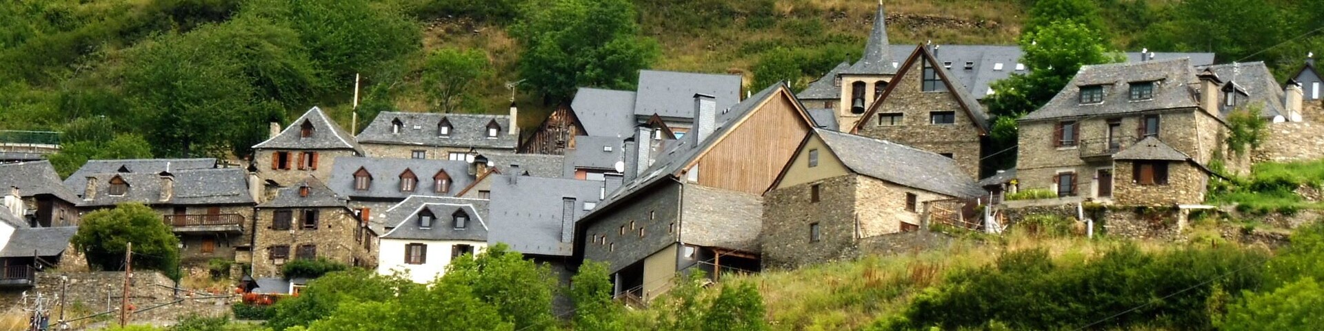 A village with stone houses and a church on a hillside.