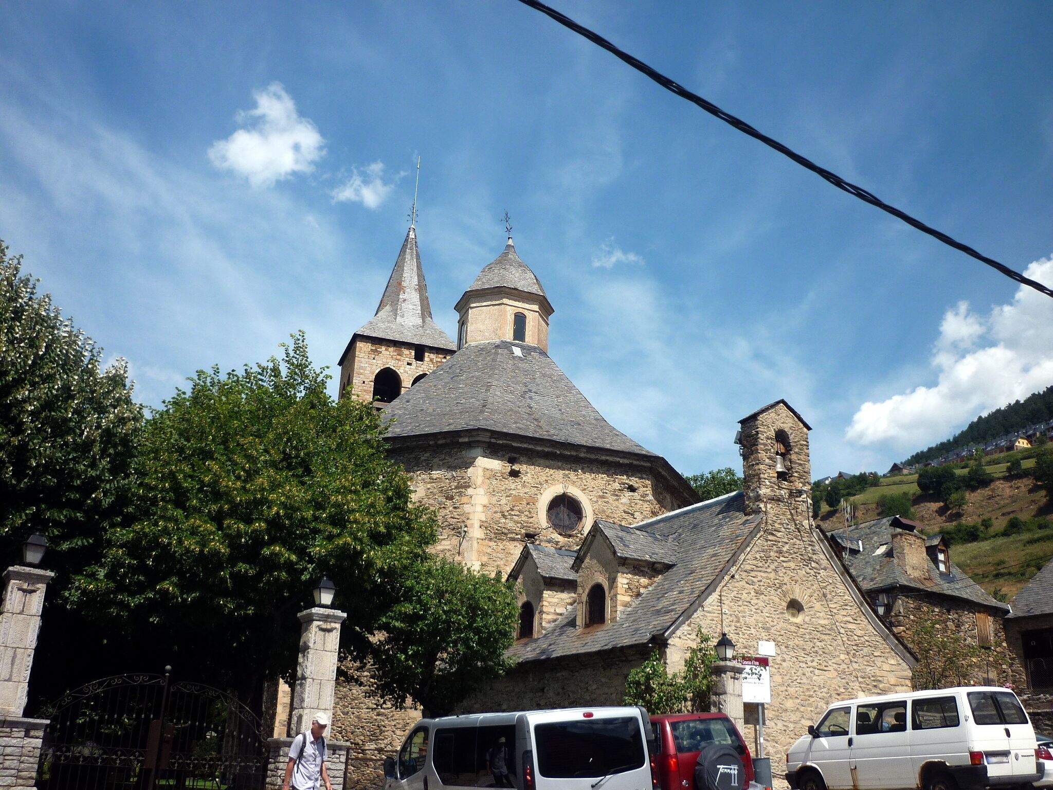 A historic church with two spires, surrounded by stone buildings and greenery.