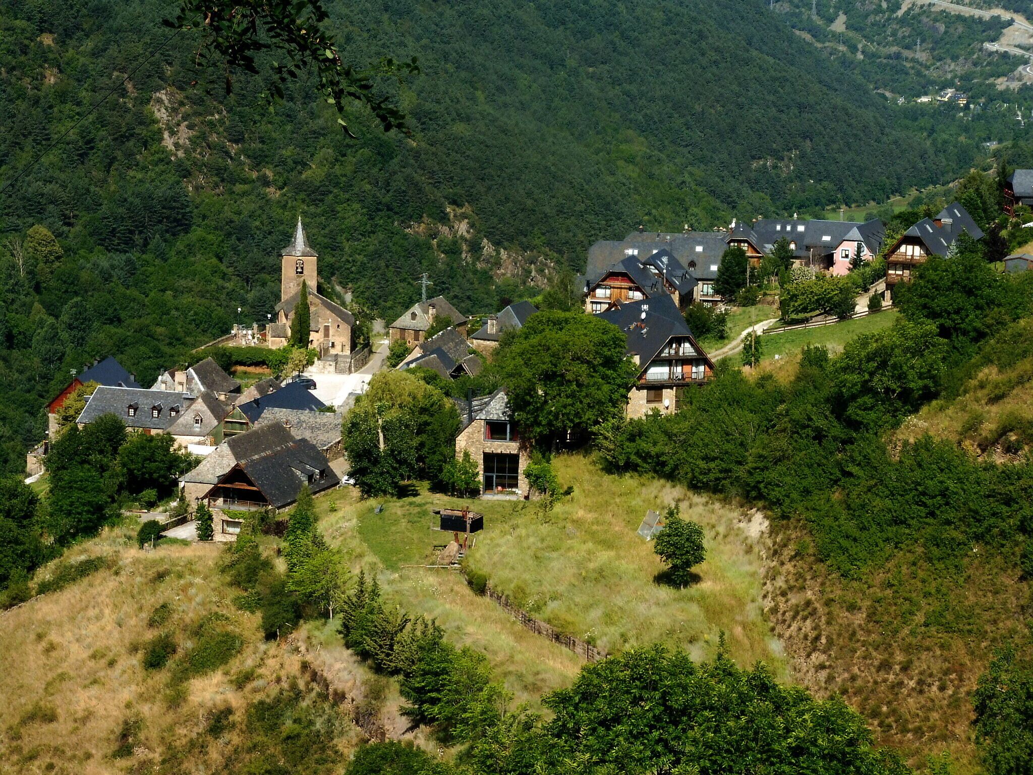 A village nestled in a valley with a church and traditional houses.