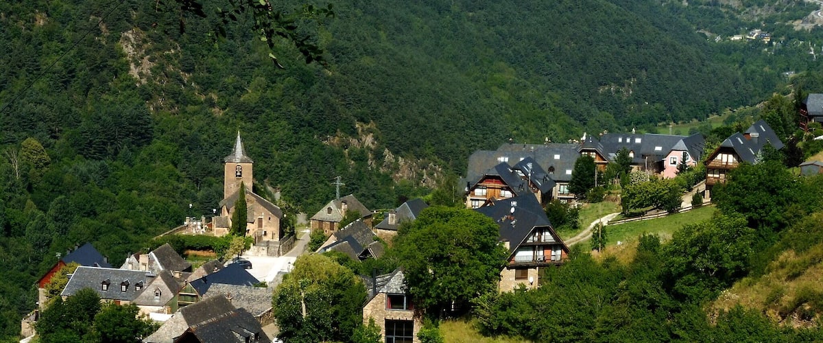 A village nestled in a valley with a church and traditional houses.