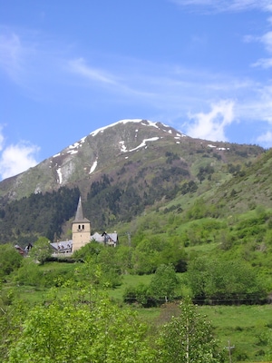 Een kerk op een heuvel, met een besneeuwde berg op de achtergrond.