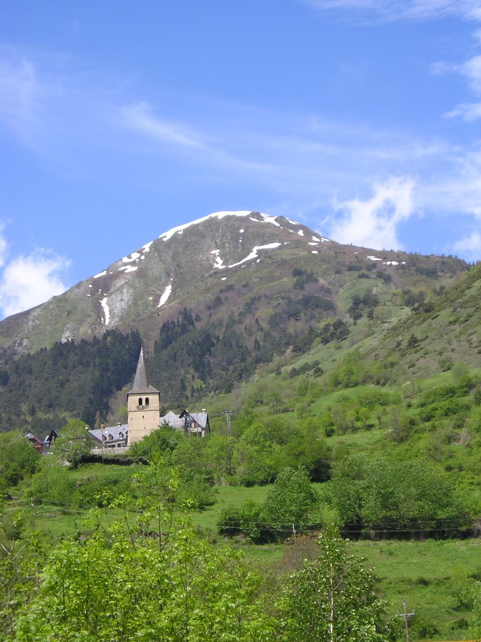A church on a hillside with a snow-capped mountain in the background.