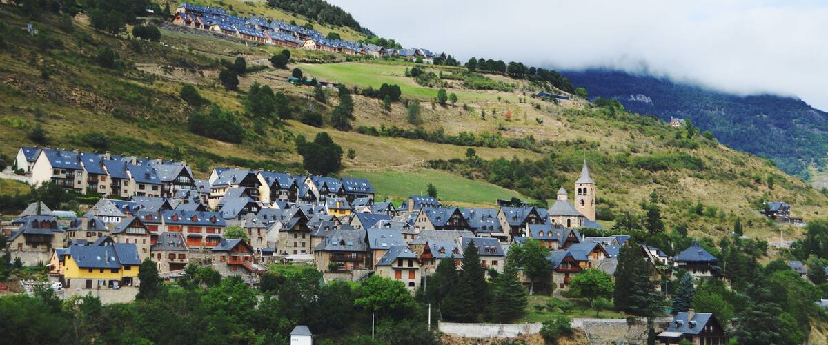 A village with traditional houses, a church, and a hill with a tower.