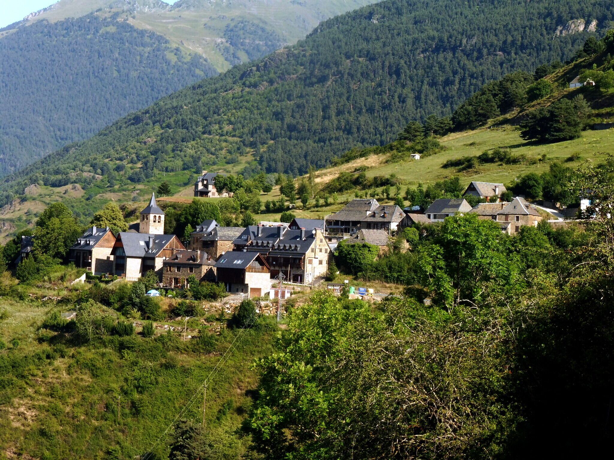 A village nestled in a valley surrounded by forested hills.