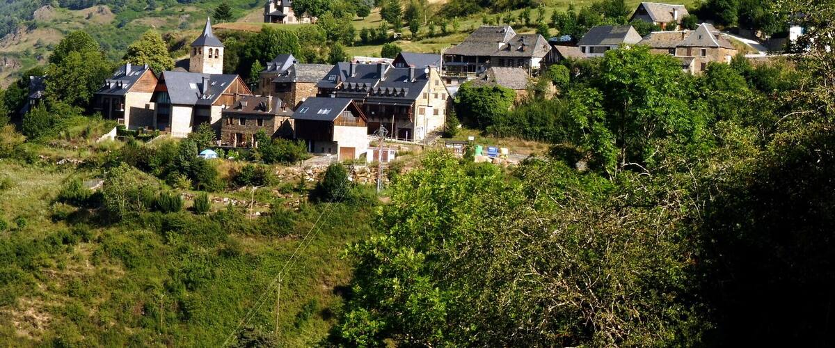 A village nestled in a valley surrounded by forested hills.