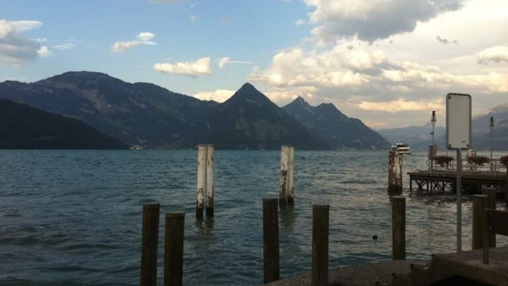 A lake with wooden posts and a dock, surrounded by mountains.